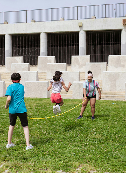teens jump roping outside in a field