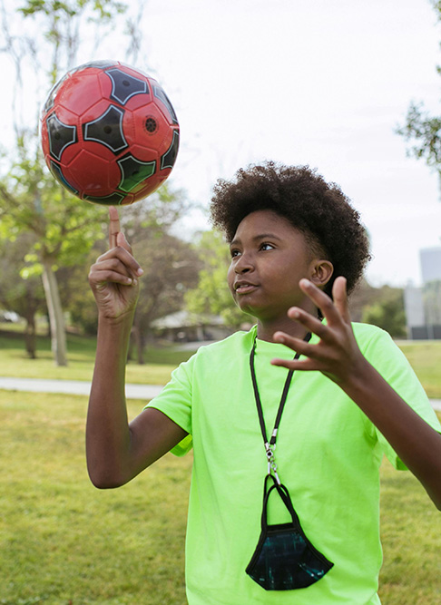 teen spinning the ball outside in a field